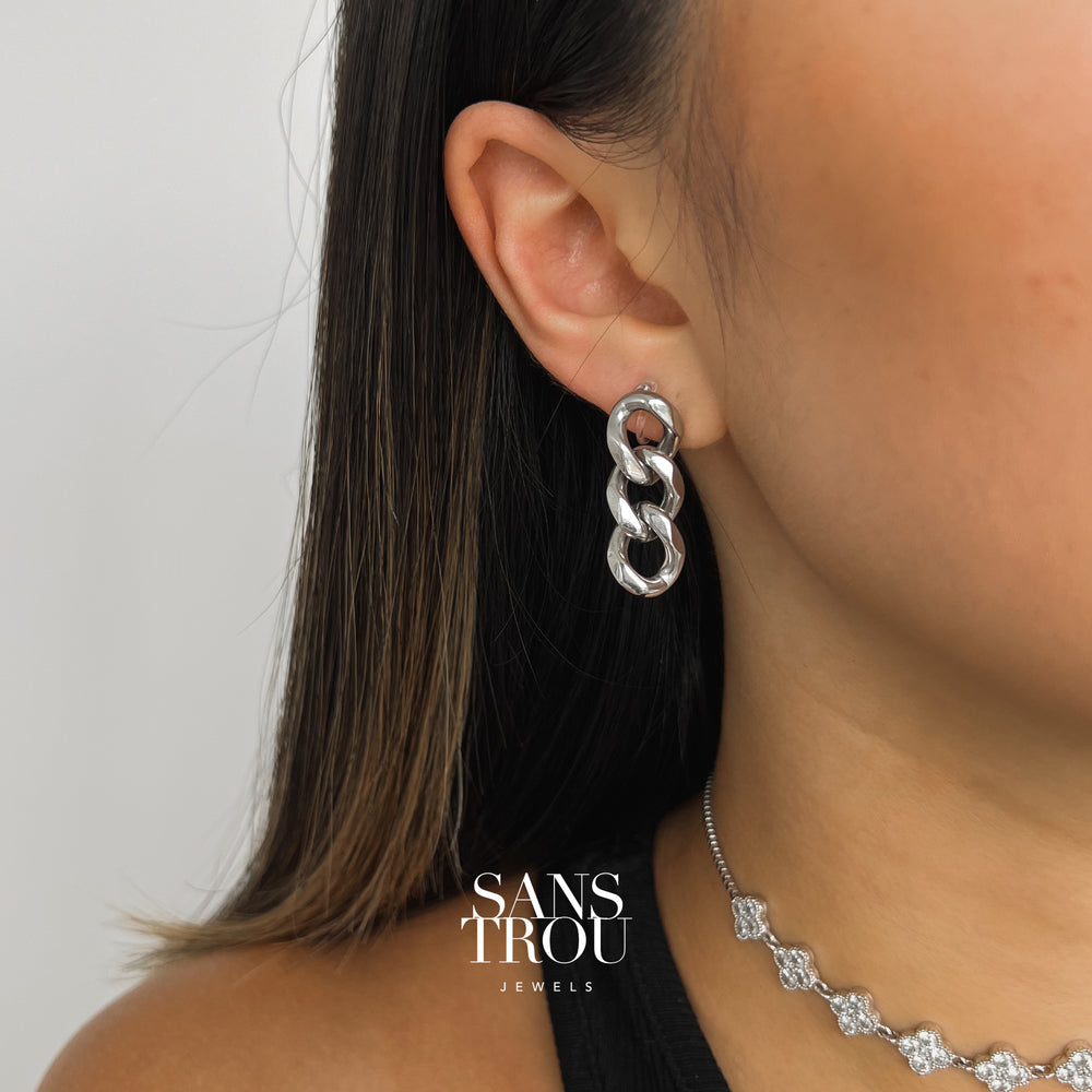 Model wears the stainless steel silver clip-on earring with a drop chain style on the lobe. 