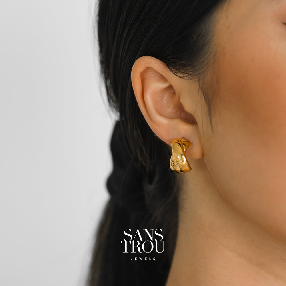 Model wears 18k gold plated chunky criss cross clip-on earring on the lobe.  