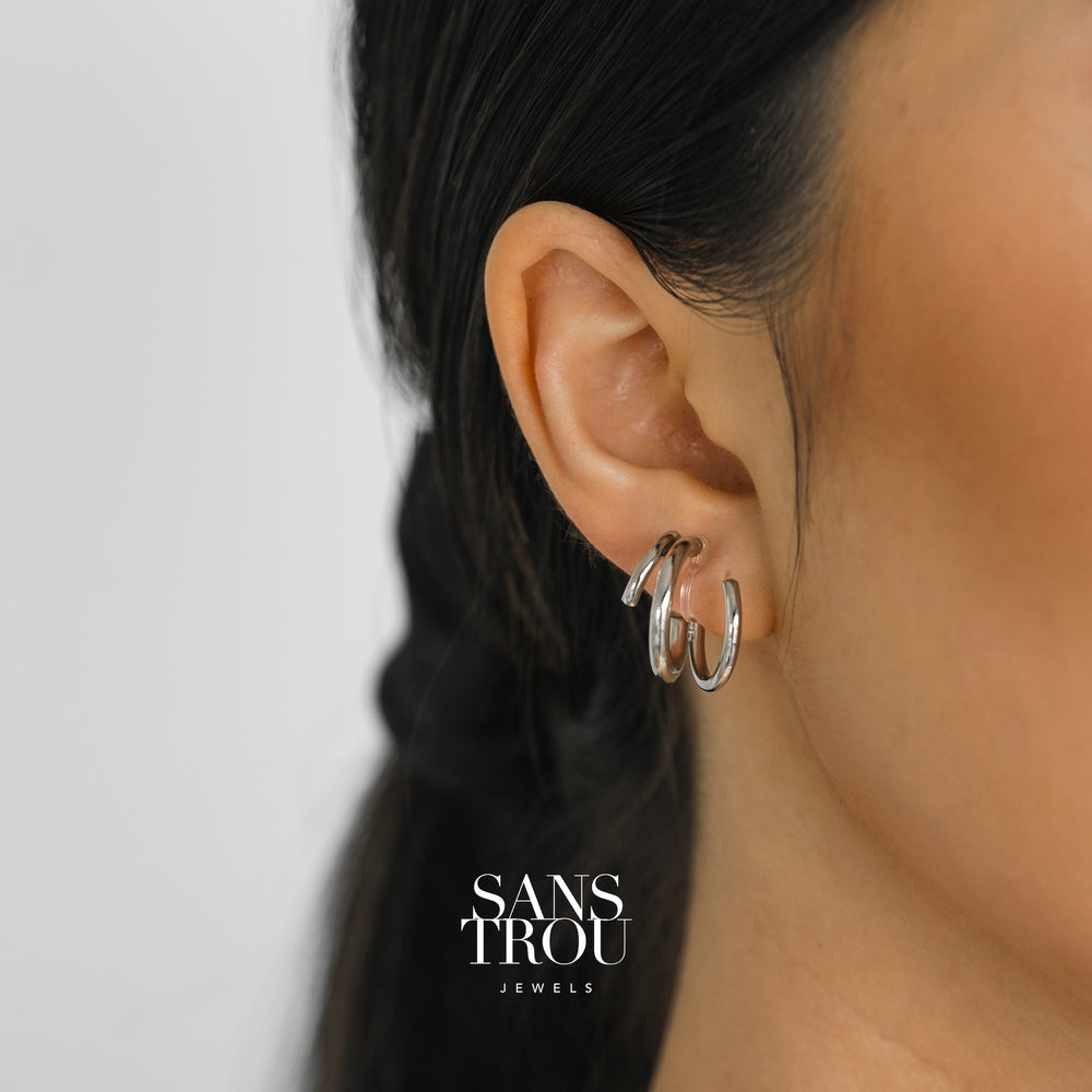 Model wears a silver spiral clip-on earring on the lobe. The earring has an asymmetrical pair. 