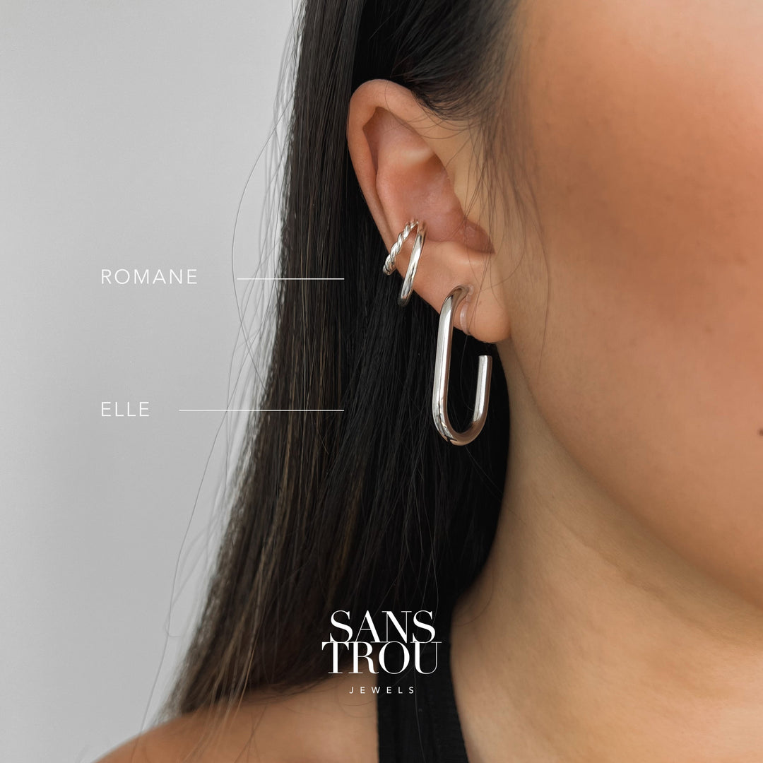 Model wears a titanium steel silver rectangular clip-on attached to the lobe by a resin clip. 