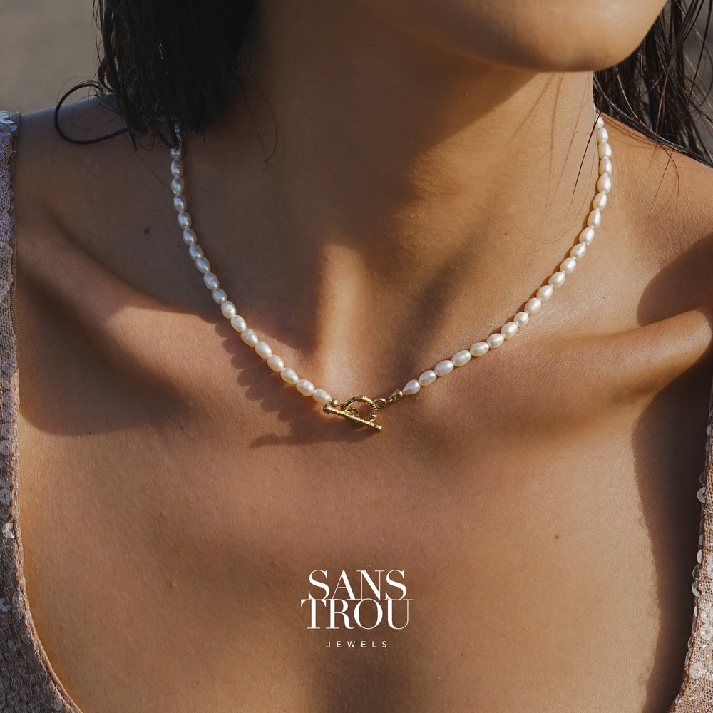 Pearl necklace with a gold toggle clasp on a person's neck