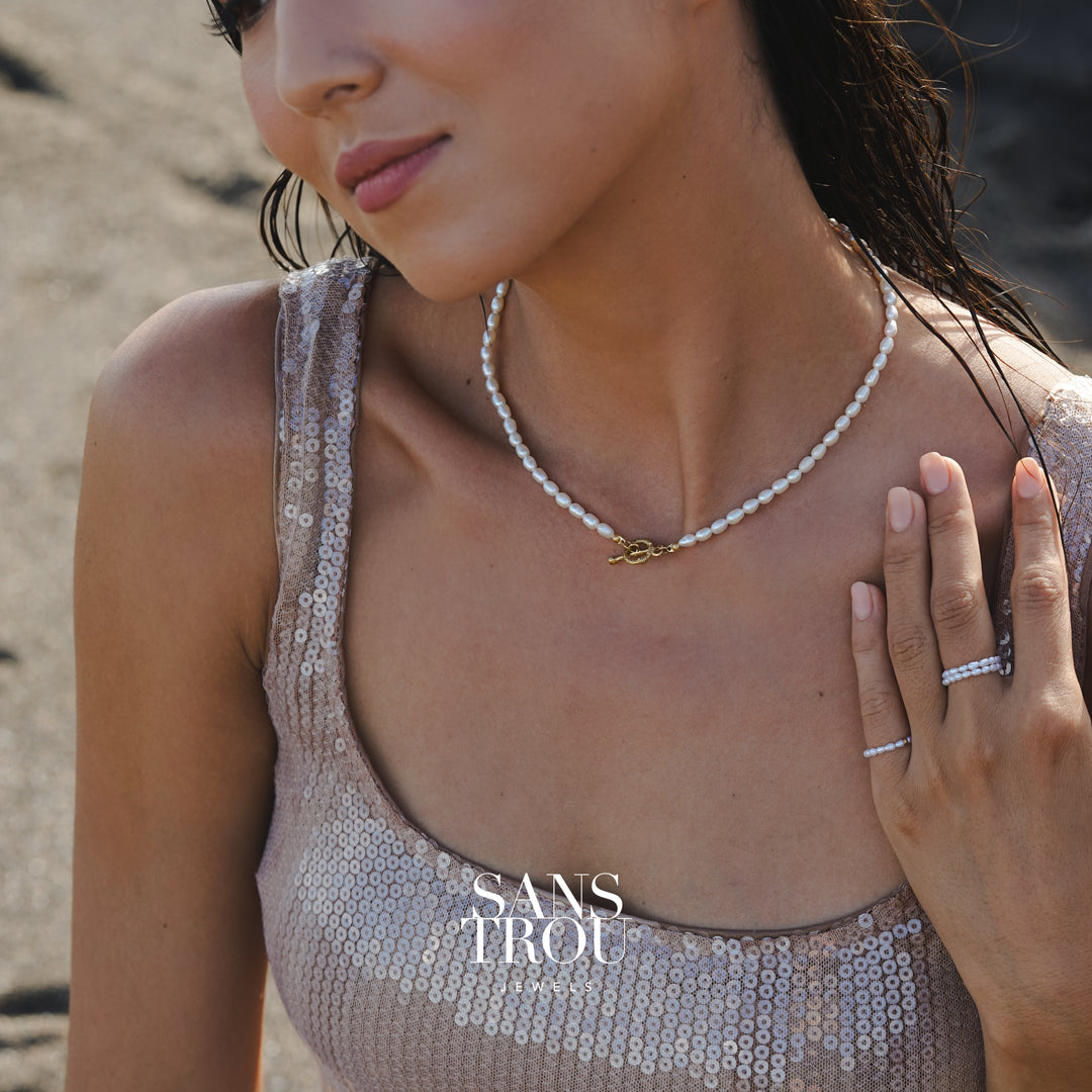 Woman wearing a sequin top and pearl necklace on a beach