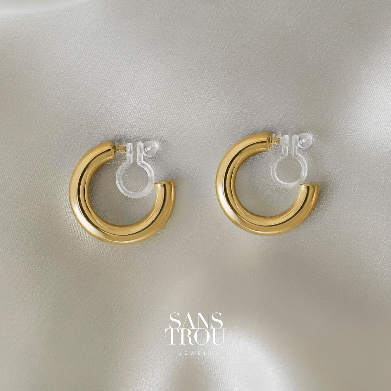 SANS TROU classic chunky clip-on hoops in 18k gold plating. Features a comfortable and discreet clear resin clip. No piercings required.
