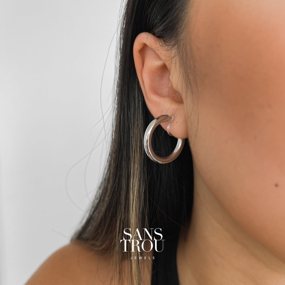 Model wearing classic silver clip-on hoops made with high polish stainless steel.