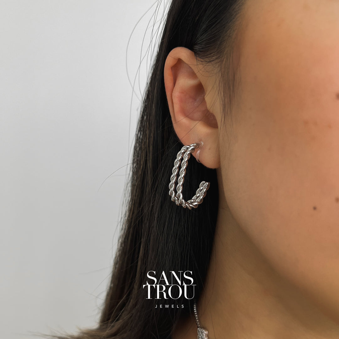 Silver clip-on earrings worn on model from front angle. Earrings feature two twisted rope bars that come together in a half hoop shape