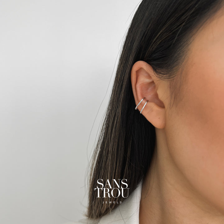 Model wears a silver ear cuff set with a rectangular slim design. This cuff set is worn as a conch piercing. 