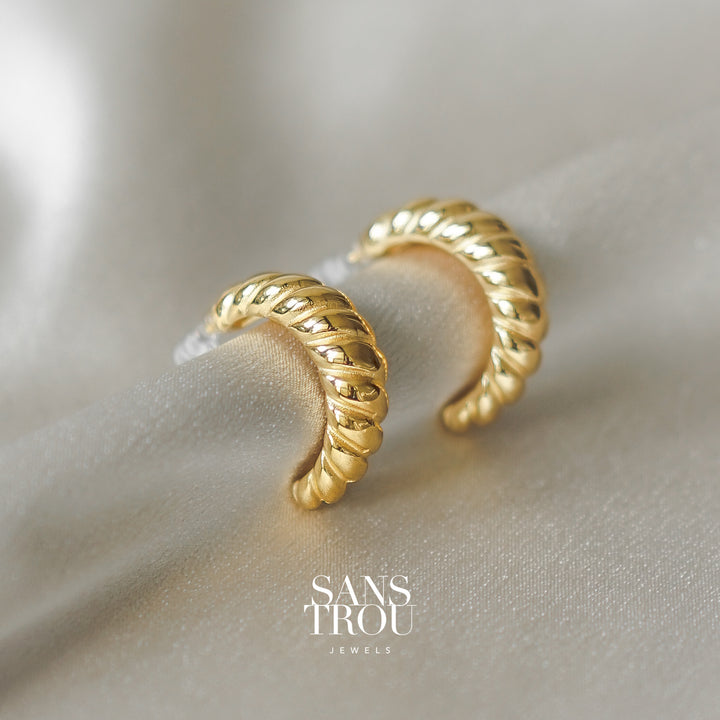 Clip-on earrings in a croissant hoop shape. 18k gold plated titanium stainless steel.  No piercings required.