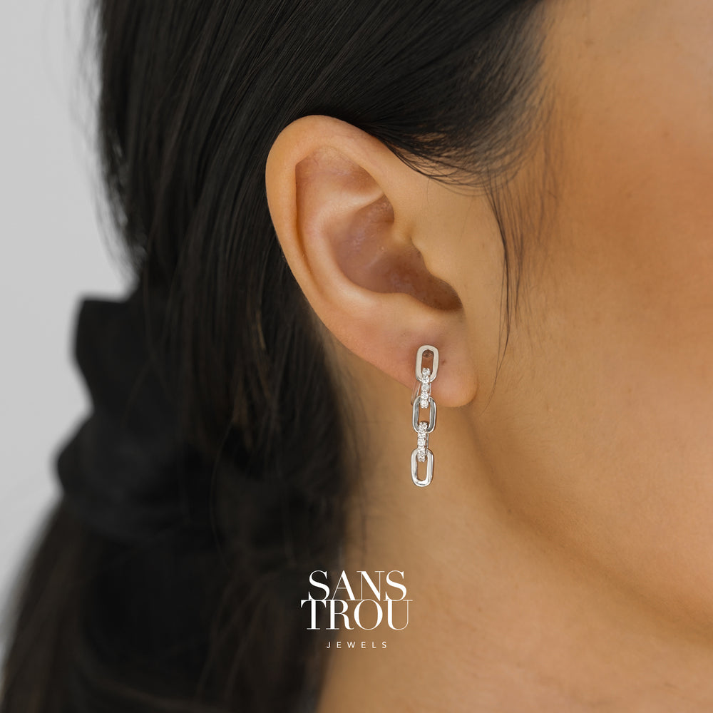 Model wears a silver three sequence chain drop-clip on earring. The earring is worn on the lobe and features CZ stones. 
