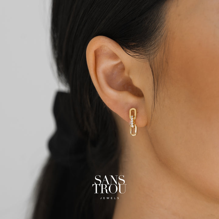 Model wears a dainty two sequence chain drop-clip on earring. The earring is worn on the lobe and features CZ stones. 