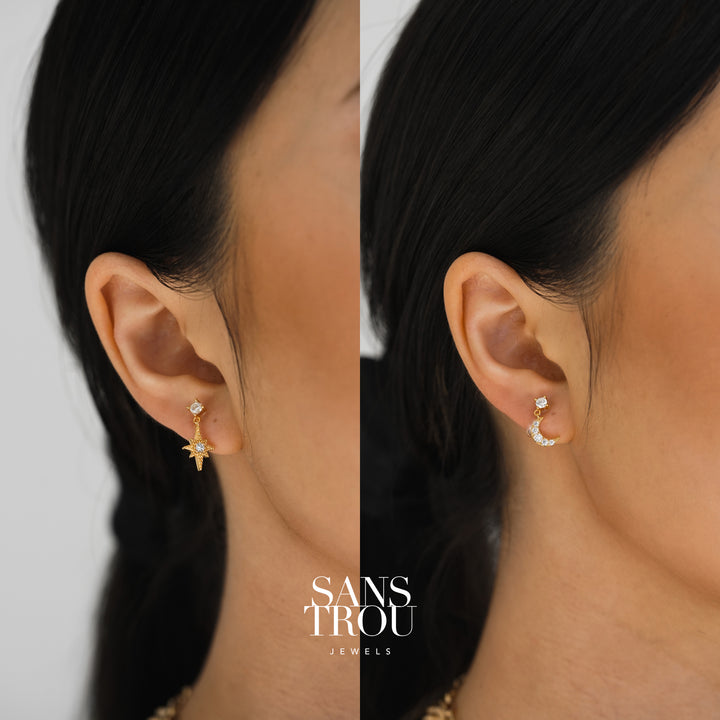 Model wears a gold asymmetrical star and moon clip-on earring set. 