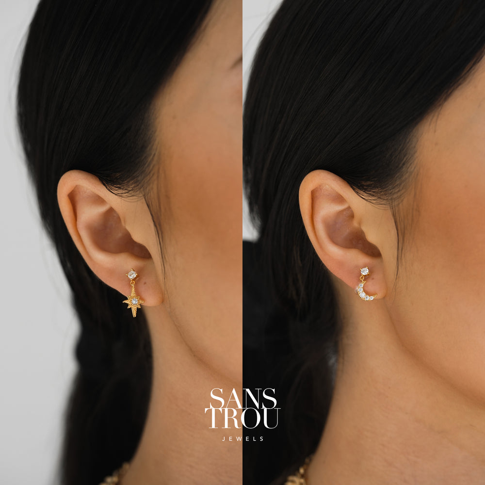 Model wears a gold asymmetrical star and moon clip-on earring set. 