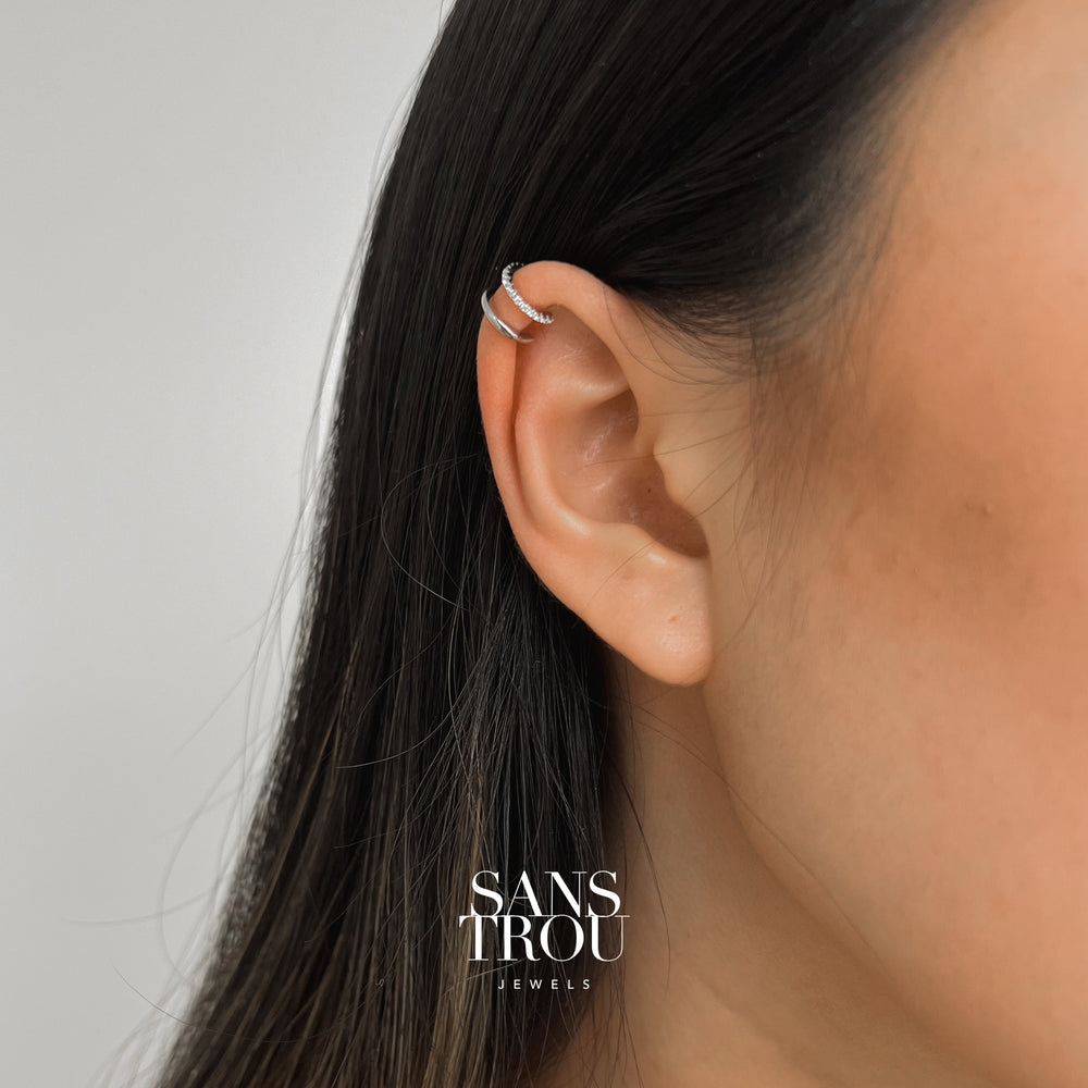Model wears double layered silver ear cuff with zircon stones on the upper helix. 