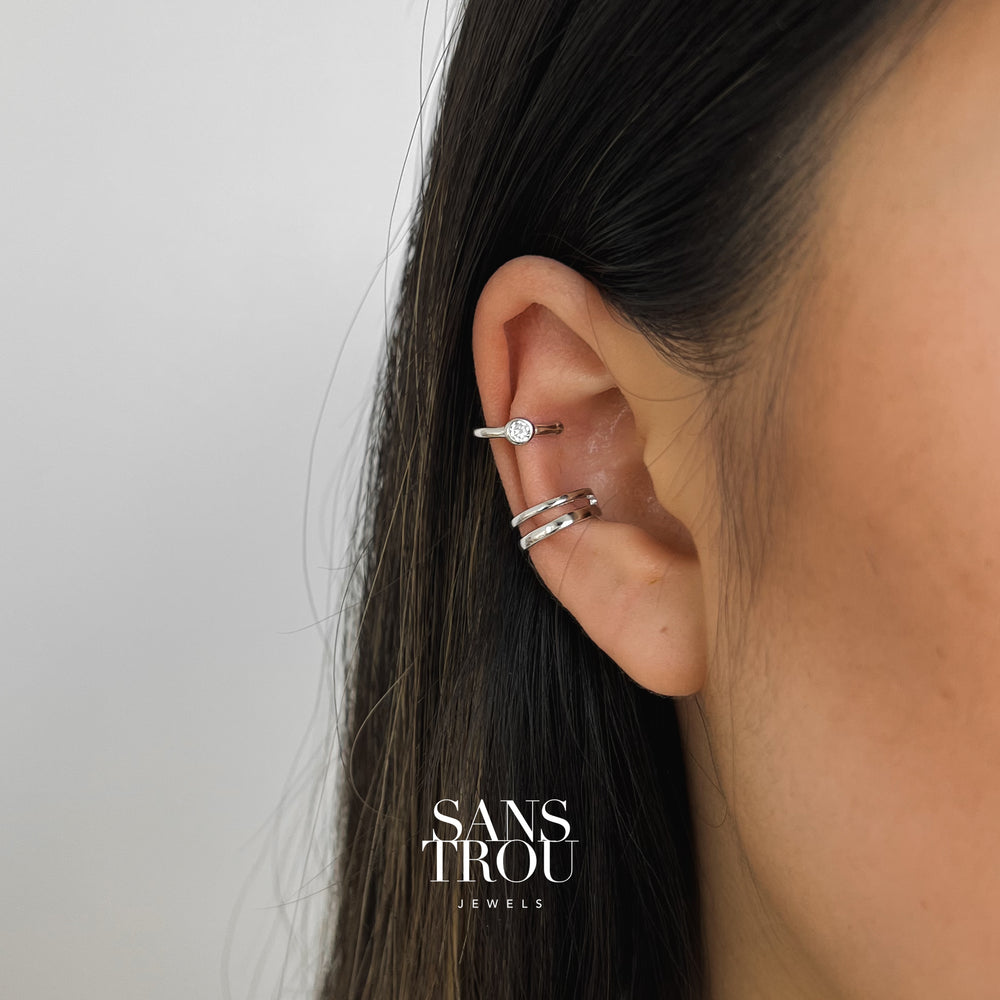Model wears sterling silver ear cuff set. The double layered cuff is positioned on the conch and CZ stone cuff can be worn on the helix. 