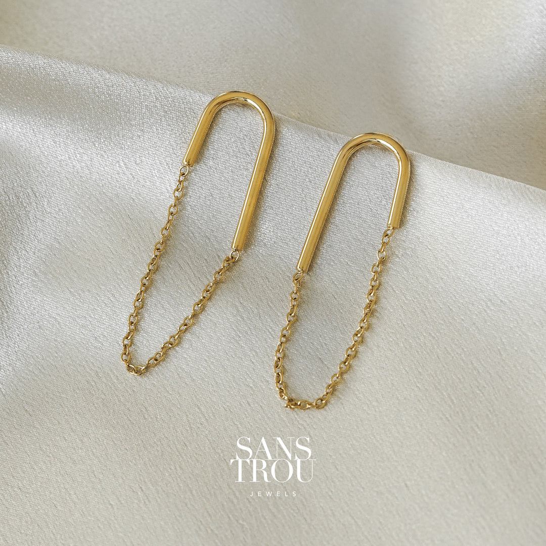 Sans Trou gold U shaped clip-on earring with an attached drop chain. The Lea is worn on the lobe and has an asymmetrical pair. 