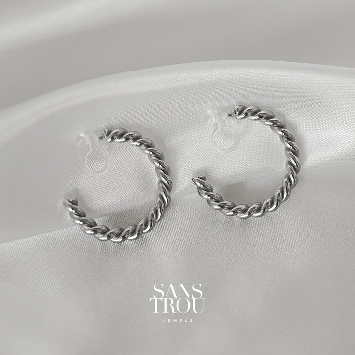 Sans Trou unique stainless steel silver clip-on hoop earring with a twisted silhouette. The Lucie is attached by a resin clip. 