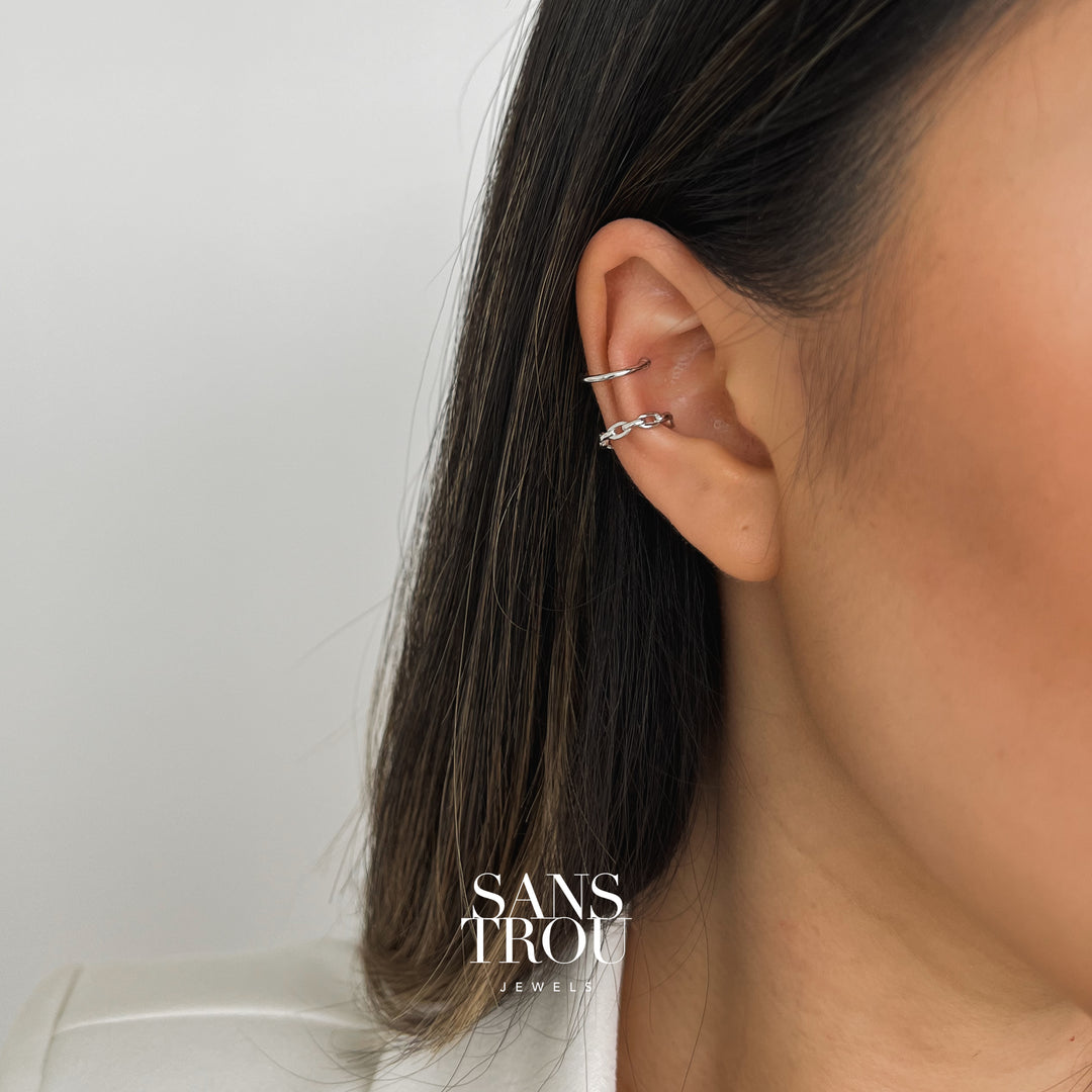 Model wears a silver single banded and rounded circle chain cuff ear cuff on the helix and conch.   