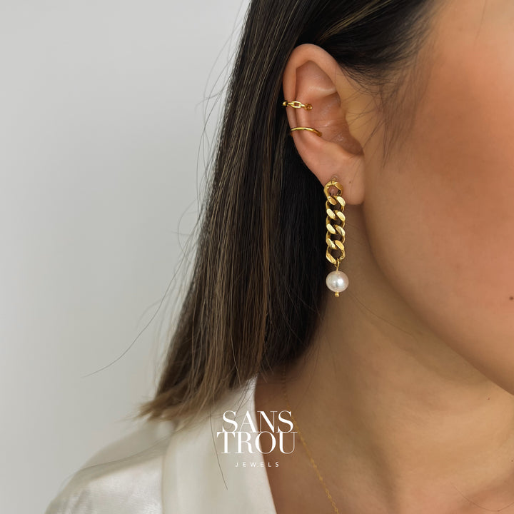 Model wears a 18k gold plated drop chain clip-on earring with an attached fresh water pearl on the lobe.  